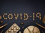 Syringes laid below pills spelling out "COVID-19"