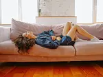 Woman lying on couch holding abdomen