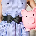 Woman in a dress holding a large piggy-bank